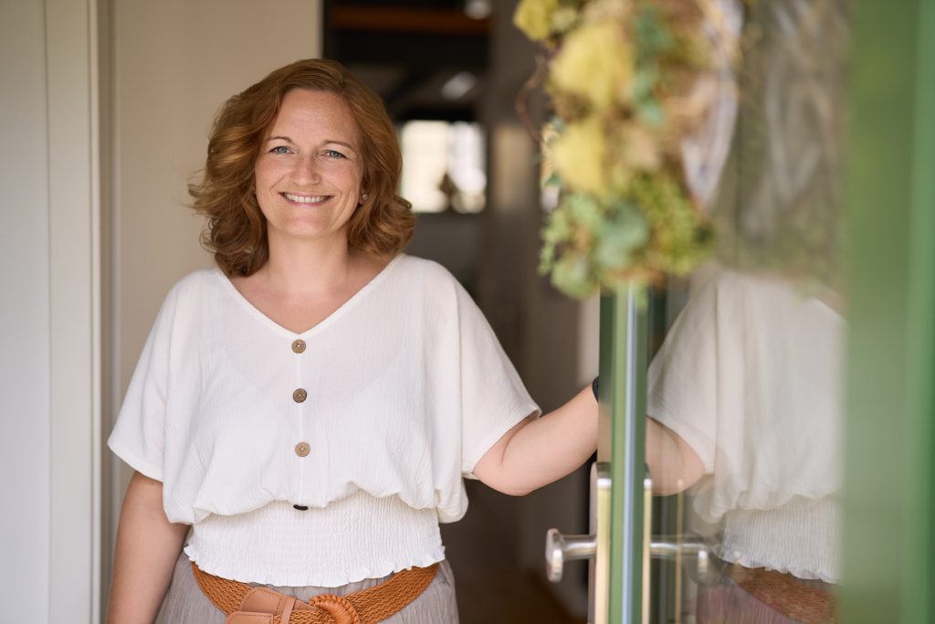 lächelnde weibliche Person an geöffneter Tür