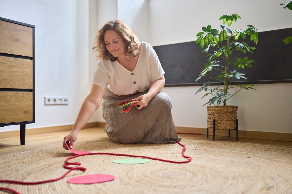 Kniende Person legt Moderationskarten entlang einer Linie